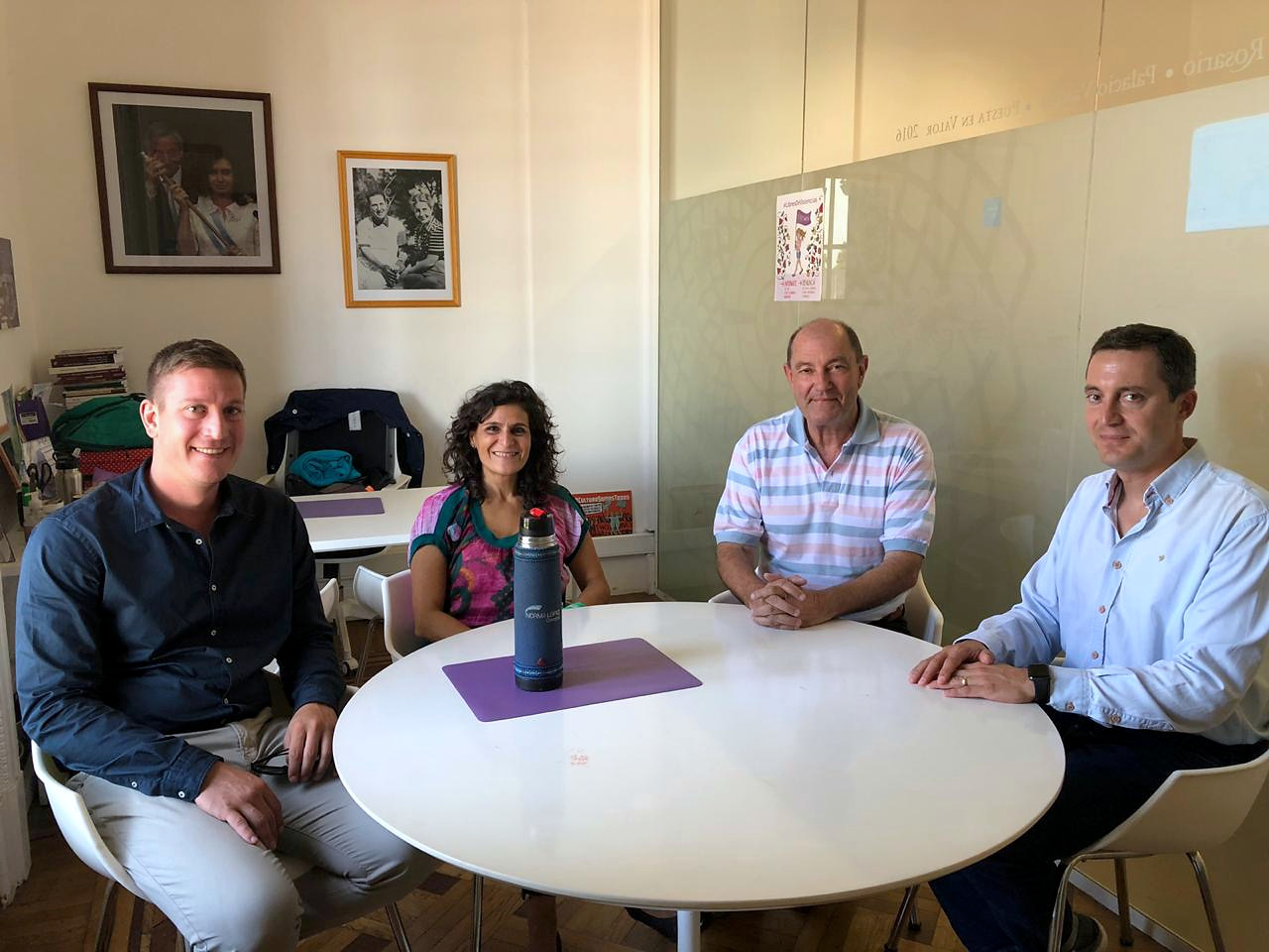 Cuatro personas reunidas alrededor de una mesa en una oficina.