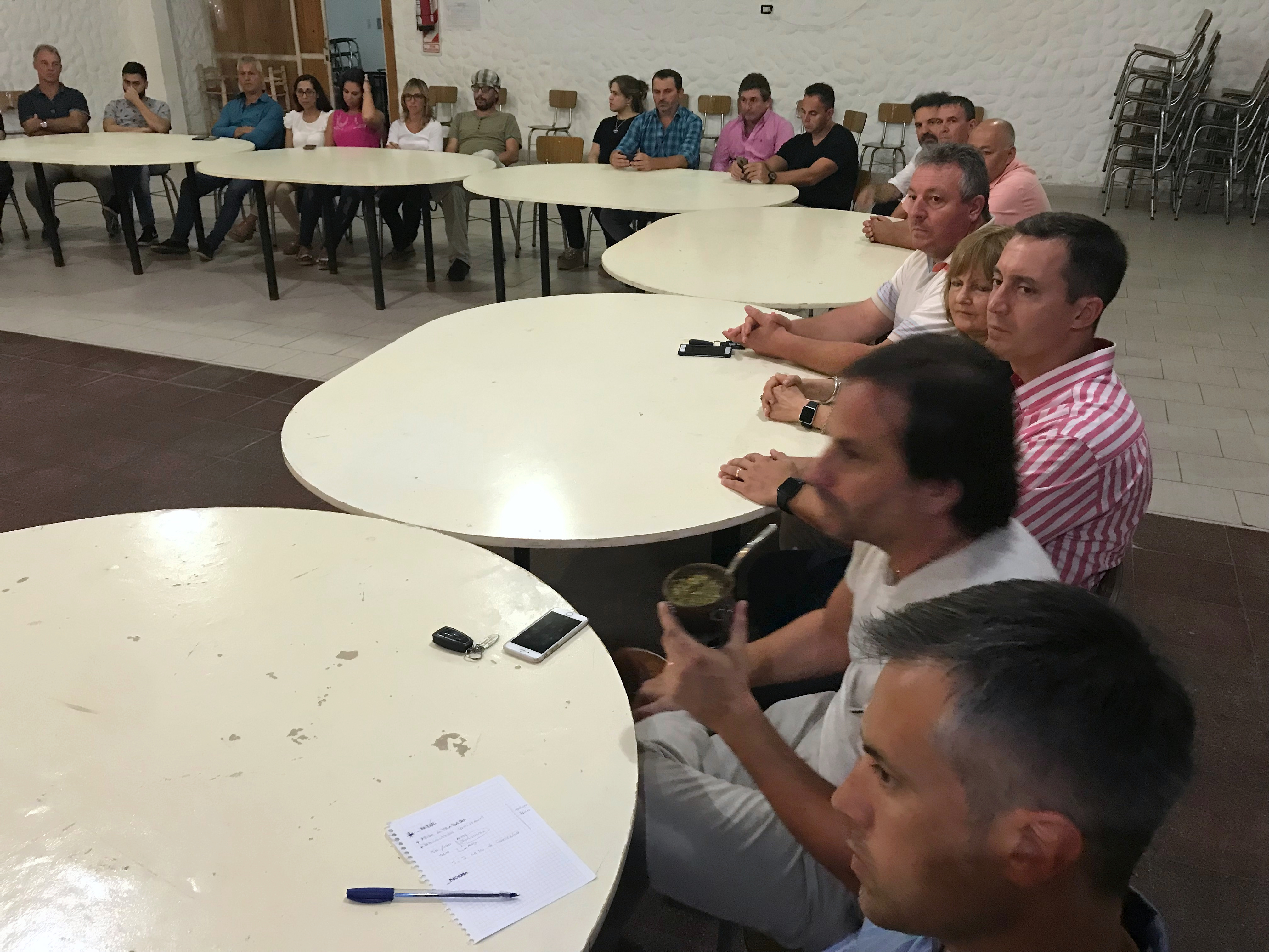 Participantes reunidos alrededor de varias mesas en un salón.