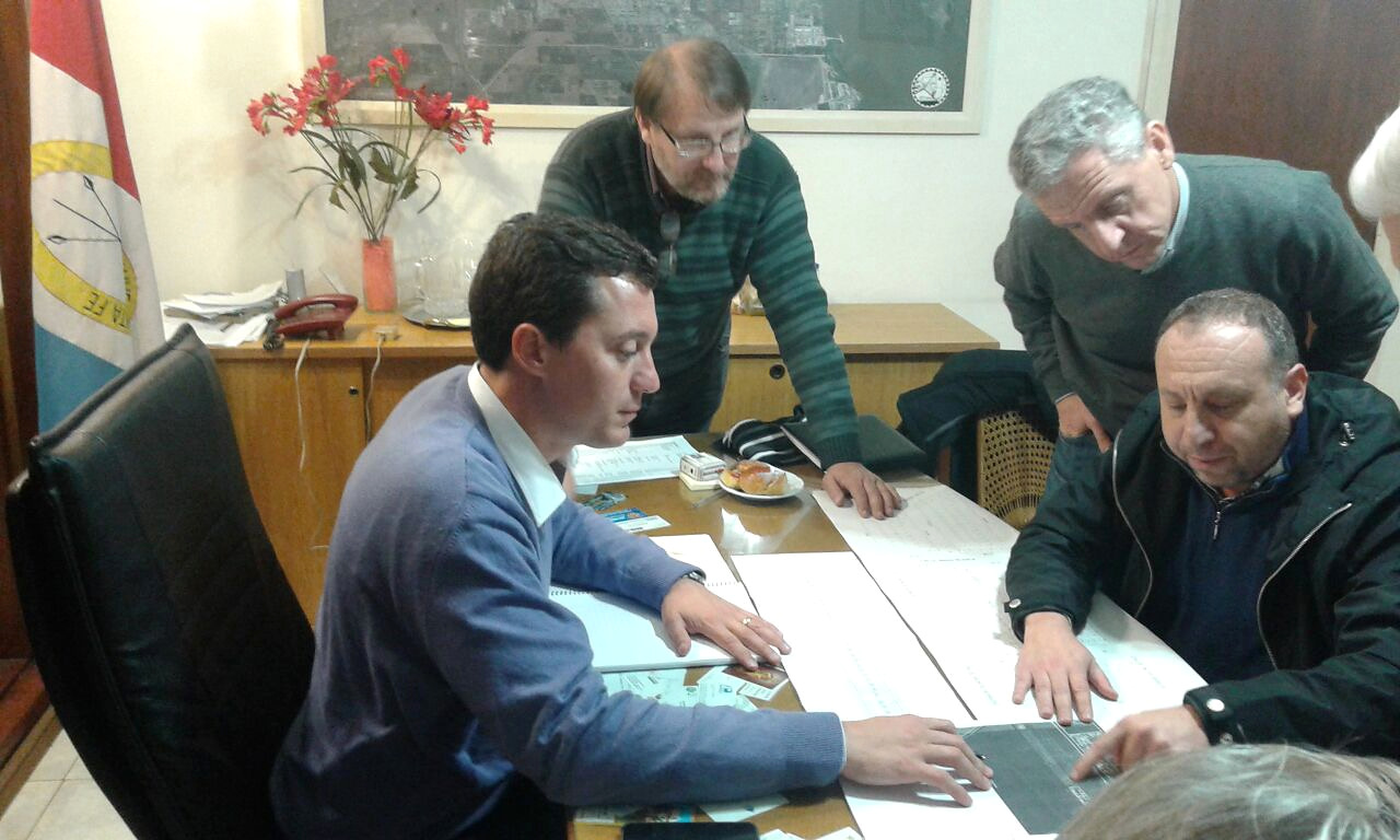 Personas reunidas alrededor de un escritorio revisan documentos.