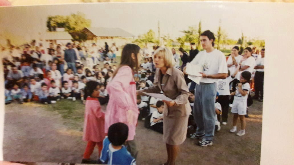 Encuentro al aire libre con entrega de documentos y público presente.